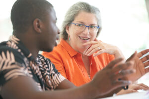 Student gesturing with his hands as he explains something to his professor, one on one