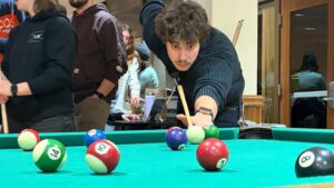 Student lining up a shot at the pool table